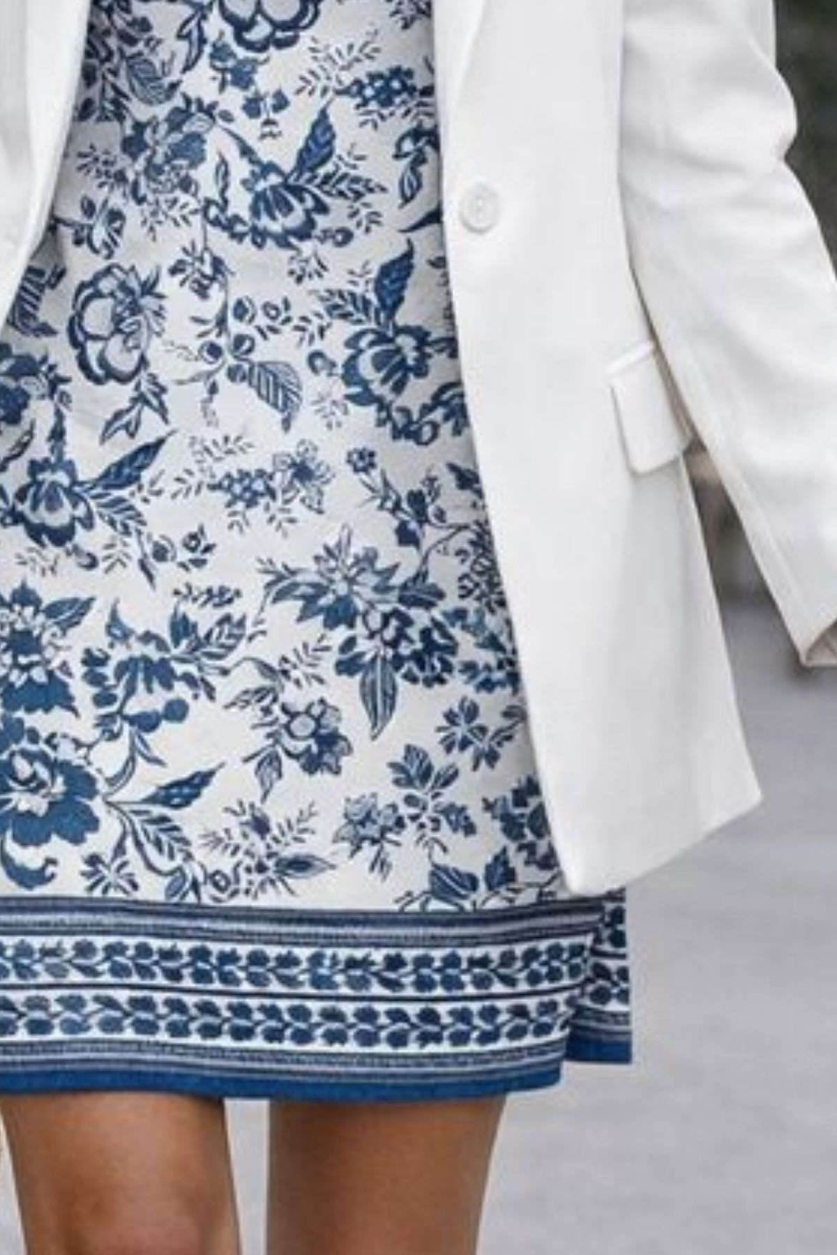 Close-up detail of a blue and white floral spring dress paired with a white blazer, showing the pattern and hemline