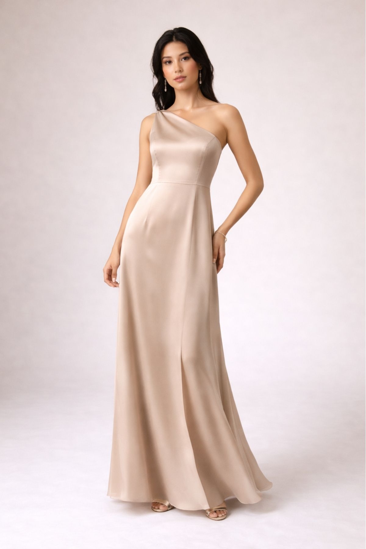 Elegant champagne one-shoulder bridesmaid dress with flowing floor-length silhouette, perfect for a modern summer wedding 2026, photographed in a minimalist studio setting.