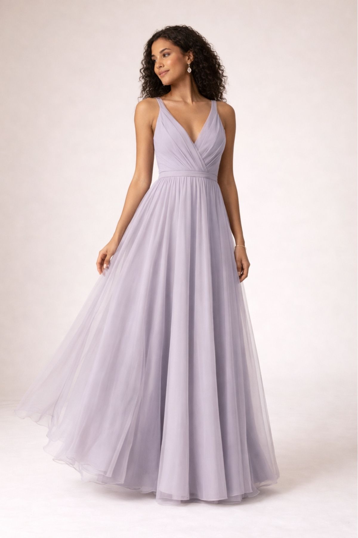 Elegant lavender tulle bridesmaid dress with V-neckline and flowing A-line skirt, perfect for a romantic summer wedding 2026, photographed in a soft neutral studio setting.