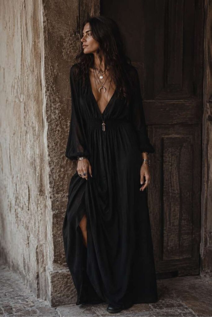Woman in long black boho maxi dress with layered jewelry and dark feminine style